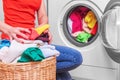 Young woman loads the laundry in the washing machine from the laundry basket before washing. Royalty Free Stock Photo