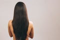 Young woman with long black hair posing on camera. Showing lenght of it. Smooth treasure. Standing back to camera. Naked