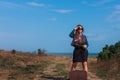 Woman with long brown hair in denim jacket, black skirt, vintage suitcase, flowers bouquet off-road. Lifestyle photo Royalty Free Stock Photo