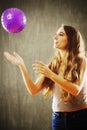 Young woman with long brown hair playing with purple ball. Royalty Free Stock Photo