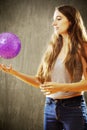 Young woman with long brown hair playing with purple ball. Royalty Free Stock Photo