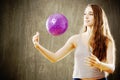 Young woman with long brown hair playing with purple ball. Royalty Free Stock Photo