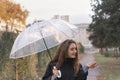 Young woman with long brown hair standing with umbrella in park. Girl with an umbrella on cloudy autumn day Royalty Free Stock Photo