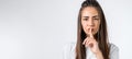 Young woman with long chestnut hair keeping index finger at her lips, saying Shh, Keep silent, It`s secret. Copy space