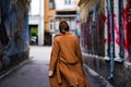 A young woman in a long coat walks the streets of the old city alone. tourist in a new city. travel alone