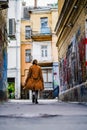 A young woman in a long coat walks the streets of the old city alone. tourist in a new city. travel alone