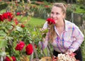 Young woman with long curly hair smells roses flower outdoor