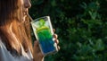 Young woman with long dark hair drinking a summer refreshing cocktail through a straw. Selective focus Royalty Free Stock Photo