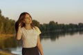 Young woman with long dark hair on the shore of the lake at sunset. Soft focus, blur