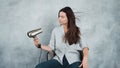 A young woman with long dark hair uses a hair dryer to dry and style. Hairstyle styling and hair care,