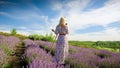 Young woman in long dress standing at easel and painting picture of lavender field