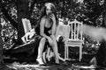 Young woman in a long evening dress sits at a table in the woods. Black and white photography Royalty Free Stock Photo