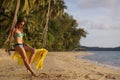 Young woman with long hair, in bikini sitting on rope swing on tropical sunny sandy beach. Girl looking down Royalty Free Stock Photo