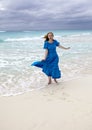 Young woman with long hair fluttering in the wind in a blue dress running along the edge of the seaCuba, Varadero Royalty Free Stock Photo