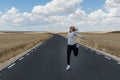 Young woman jumping on the road on nowhere