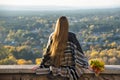 Young woman with long hair sits on a hill overlooking the city. Royalty Free Stock Photo