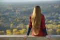 Young woman with long hair sits on a hill overlooking the city. Royalty Free Stock Photo