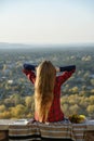 Young woman with long hair sits on a hill overlooking the city. Royalty Free Stock Photo