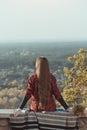 Young woman with long hair sits on a hill overlooking the village. Back view Royalty Free Stock Photo