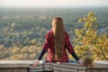 Young woman with long hair sits on a hill overlooking the village. Back view Royalty Free Stock Photo