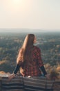 Young woman with long hair sits on a hill overlooking the village. Back view Royalty Free Stock Photo