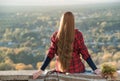 Young woman with long hair sits on a hill overlooking the village. Back view Royalty Free Stock Photo