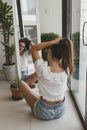 Young woman with long hair sitting on the floor in front of the mirror and making a pony tail Royalty Free Stock Photo