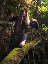 Young woman with long hair in suit of witch in forest