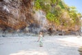 Young woman standing on the beach in front of the rocks Royalty Free Stock Photo