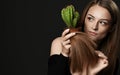 Young woman with long silky straight hair compares hair split ends with cactus plant in pot she holds looks aside Royalty Free Stock Photo