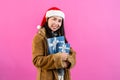 young woman in long-sleeved shirt with fluffy because cold on christmas night, held out hand receive gift box