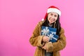 young woman in long-sleeved shirt with fluffy because cold on christmas night, held out hand receive gift box