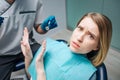 Young woman look afraid. She sit in chair in dentistry. Woman look on camera and push away doctor. He hold dentist`s