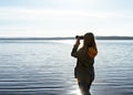 Young woman looking through binoculars at birds on lake Birdwatching, zoology, ecology. Research in nature, observation of animals Royalty Free Stock Photo