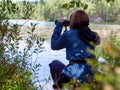 Young woman looking through binoculars at birds on the lake. Birdwatching, zoology, ecology. Research in nature Royalty Free Stock Photo