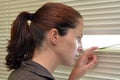 Young woman looking through blinds