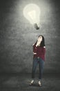 Young woman looking at a bright bulb Royalty Free Stock Photo