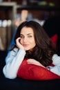 Young woman looking at the camera is lying on a couch resting her head on a pillow Royalty Free Stock Photo