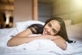 Young woman looking at camera and smiling while lying on the bed at home Royalty Free Stock Photo