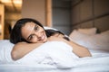 Young woman looking at camera and smiling while lying on the bed at home Royalty Free Stock Photo