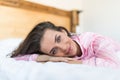 Young woman looking at camera and smiling while lying on the bed at home Royalty Free Stock Photo