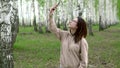 A young woman is looking for a cellular network in a birch forest. A girl is talking on the phone, but the connection is Royalty Free Stock Photo