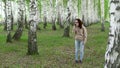 A young woman is looking for a cellular network in a birch forest. A girl is talking on the phone, but the connection is Royalty Free Stock Photo