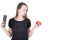 Young woman looking between chocolate bar and fresh red apple Royalty Free Stock Photo