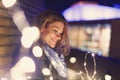 Young woman looking down to fairy lights outdoors