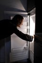 Young woman looking into the fridge looking for food , feeling hungry at night. Night snacking and unhealthy lifestyle Royalty Free Stock Photo