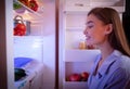 Young woman looking for healthy snack in fridge late in night Royalty Free Stock Photo