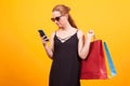 Young woman looking into her phone and holding colorful shopping bags Royalty Free Stock Photo