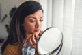 Young woman looking herself in the mirror at home. Worried about acne caused by wearing a mask Royalty Free Stock Photo