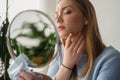 Young woman looking herself in the mirror at home. Worried about acne caused by wearing a mask Royalty Free Stock Photo